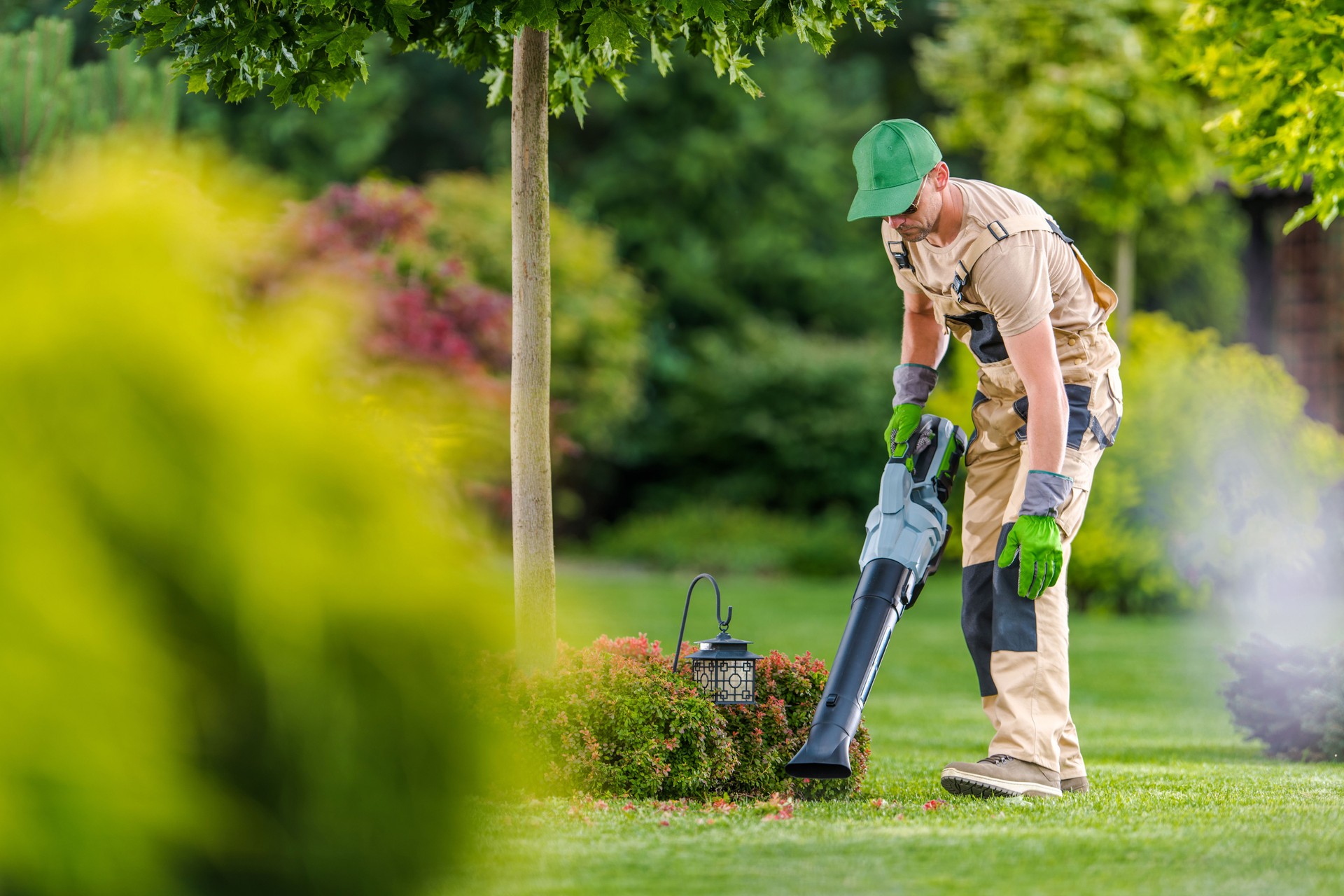 Gardener with Cordless Leaf Blower Cleaning Backyard Garden